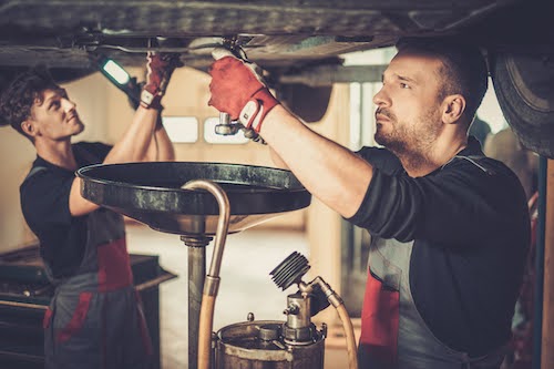 professional auto mechanics performing an oil change